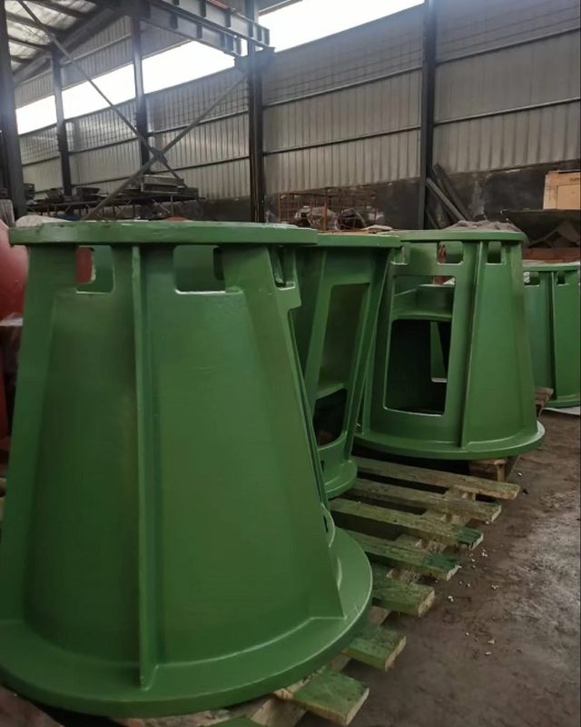 Green-primed conical ductile iron motor stool castings on pallets at the foundry